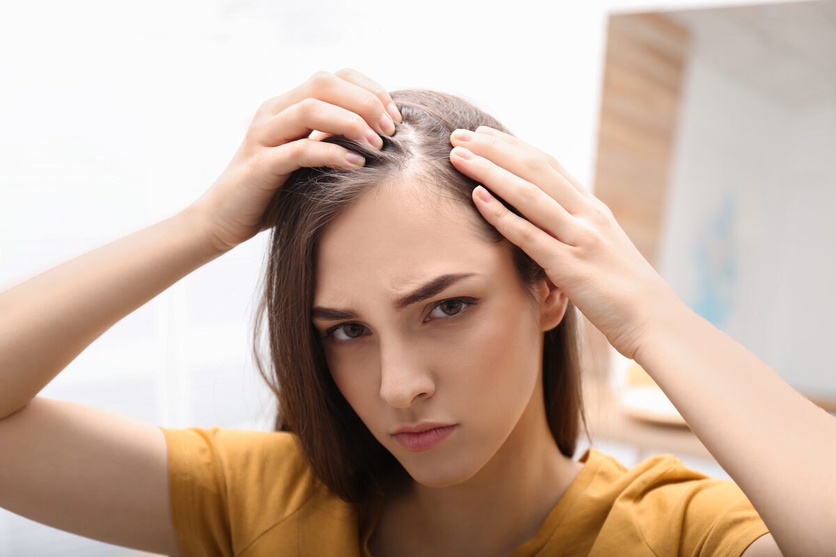Woman examining a widening part and thinning hairline